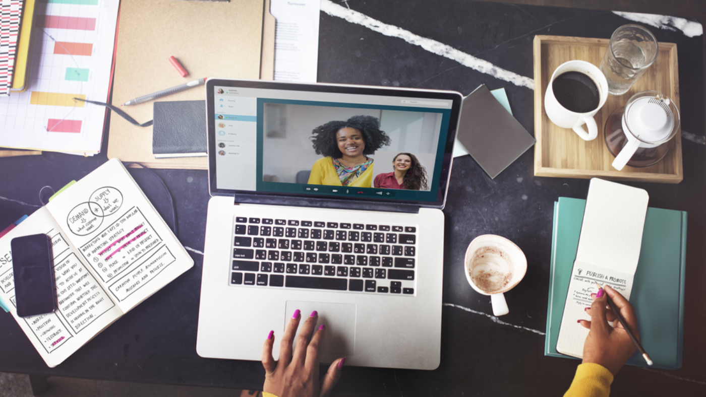 Woman video chatting with her co-workers on a laptop